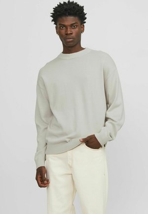 Light gray crewneck sweater with ribbed cuffs and hem, paired with off-white jeans. Soft, textured fabric with a relaxed fit.