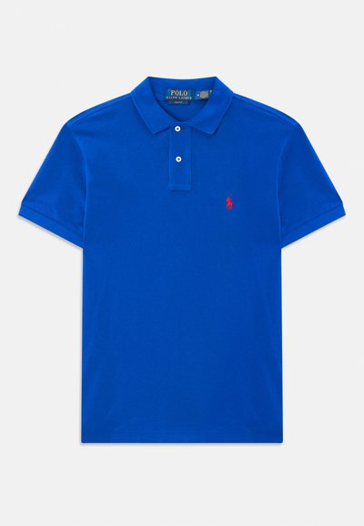 Zils īsām piedurknēm polo krekls ar diviem pogām, apkakli un mazu sarkanu izšuvumu logo kreisajā krūtī.