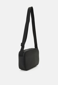 Black crossbody bag made of textured synthetic material. Features a slim rectangular shape and an adjustable strap.