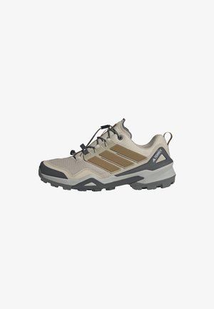 Chaussure de randonnée Adidas Terrex couleur marron clair et gris avec une semelle texturée, un système de laçage rapide et un soutien de cheville rembourré, vue de côté.