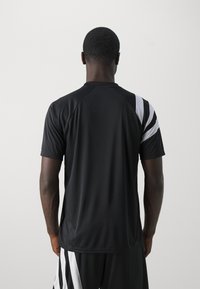 Černý sportovní dres s kulatým výstřihem a krátkými rukávy, zdobený bílými diagonálními pruhy na pravém rameni a boku.