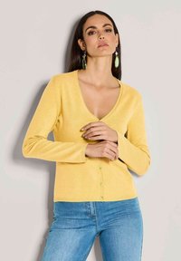 Gelbe Strickjacke mit tiefem V-Ausschnitt, langen Ärmeln und einer Knopfleiste mit hellgrünen Knöpfen; weicher Stoff und taillierte Passform.