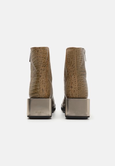 Cizme de gleznă din piele maro cu textură de crocodil, toc metallic pătrat și fermoare laterale. Finisaj neted și design modern.