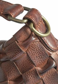 Borsa in pelle marrone con texture intrecciata, dotata di un grande anello in ottone e dettagli di cucitura a contrasto. Finitura liscia e bordi morbidi.