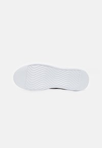Suola di sneaker bianca con un motivo testurizzato e ondulato. Punta arrotondata e tacco piatto. Design semplice senza branding o dettagli visibili.