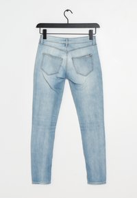 Jeans skinny de mezclilla azul claro colgados, con un diseño clásico de cinco bolsillos, fabricados con un tejido ligeramente desgastado y una cinturilla recta.