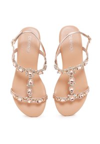 Sandalias de oro rosa con un diseño de tira T, adornadas con piedras preciosas claras y rosas. Suela suave; tira del tobillo ajustable.