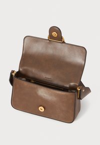 Bruine leren handtas met een gladde textuur, gouden hardware, magnetische drukknoopsluiting en een ritssluiting binnenvak. Het open ontwerp toont de binnenkant.