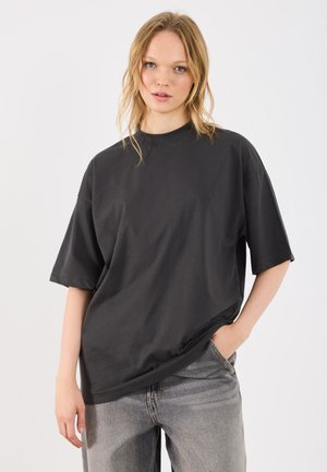 Zwarte oversized t-shirt van katoen, met korte mouwen en een ronde hals, gecombineerd met lichtgrijze jeans met vervaging.