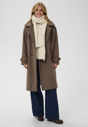 Brown wool blend overcoat with large lapels, double-breasted buttons, and pockets, paired with a textured cream scarf and wide-leg jeans.