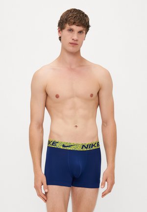 Marineblaue Boxershort mit einem gelb-grünen gemusterten Bund, der das Nike-Logo trägt. Hergestellt aus glattem, dehnbarem Stoff für optimalen Komfort.