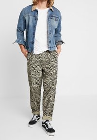 Denim jacket with a light blue hue, beige collar, white t-shirt, leopard print pants, and black sneakers with white soles.