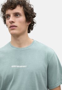 Camiseta de algodón verde menta con cuello redondo y mangas cortas, que presenta el texto "PORQUE NO HAY UN PLANETA B" en blanco.