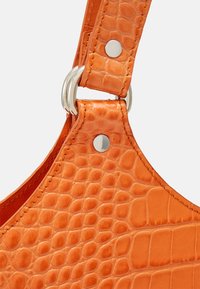 Sangle de sac à main en cuir à motif crocodile orange avec un détail en métal argenté brillant et une texture lisse. Bord cousu visible.