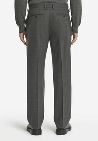 Grå skräddarsydda byxor med en slät yta, raka ben och två bakfickor med knäppningar. Bärs med svarta skor.