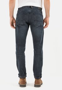 Dunkelblaue Denim-Jeans mit geradem Schnitt, fünf Taschen und umgeschlagenen Manschetten. Sie weisen eine subtile Ausbleichung und eine strukturierte Oberfläche auf.