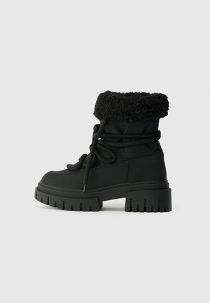 Botine negre până la gleznă, cu o margine texturată din blană, șireturi în față, talpă din cauciuc și toc gros. Material neted, cu un design robust și masiv.
