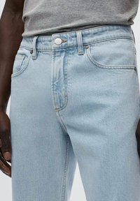 Jeans de denim en azul claro con corte recto, que cuentan con un cierre de botones, dos bolsillos frontales y una textura sutilmente desgastada.