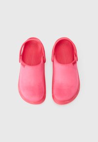 Ein Paar leuchtend pinkfarbene Clogs mit Riemen an der Ferse, aus weichem Obermaterial und strukturiertem Boden, von oben auf weißem Hintergrund gezeigt.