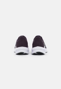 Des chaussures de sport violettes avec un dessus en mesh, une semelle intercalaire blanche et une semelle extérieure en caoutchouc noir ; la vue arrière montre la texture et les détails de conception.