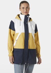 Giacca impermeabile a blocchi di colore con pannelli gialli, bianchi e blu navy; presenta un cappuccio, cordino e chiusura a scatto.