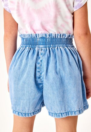 Shorts din denim de culoare bleu deschis, cu un talie elastică strânsă, buzunare laterale și o croială lejeră, având un tiv destrămat și o textură moale.