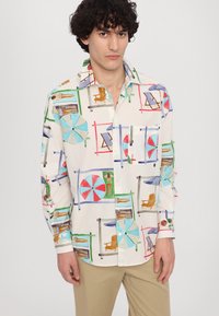 Kurzarmhemd mit Knopfleiste aus cremefarbenem Stoff, das bunte Strandmuster zeigt, darunter Sonnenliegen und Sonnenschirme.