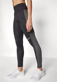 Svarta och grå träningsleggings med hög midja, försedda med en Champion-logotyp, slät textur och en elegant, åtsittande design.