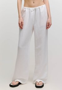 Weiße Leinen-Hosen mit weitem Bein, elastischem Bund und verstellbarem Kordelzug. Weiche Textur, fließendes Design und lockere Passform.