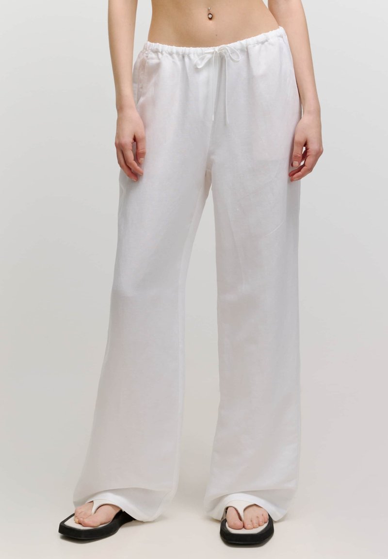 Weiße Leinen-Hosen mit weitem Bein, elastischem Bund und verstellbarem Kordelzug. Weiche Textur, fließendes Design und lockere Passform.