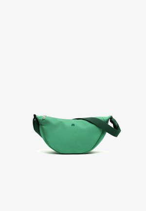 Sac vert en forme de croissant avec une large sangle réglable, un petit logo à l'avant et une fermeture éclair supérieure visible, sur fond blanc.