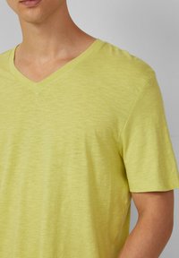 Lichtgele V-hals t-shirt gemaakt van zachte, gestructureerde stof. Korte mouwen met een gladde afwerking en een ontspannen pasvorm.