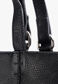 Asa de bolso de cuero negro texturizado con remaches metálicos, que presenta un acolchado detallado y un acabado suave. La vista en primer plano resalta la artesanía.