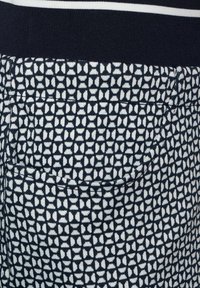 Marinblå och vit mönstrad tyg med geometriska former. Har en bakficka och en ribbad midja med ränder. Mjuk textur.