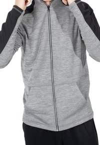 Giacca grigia con zip e dettagli neri sulle spalle. Presenta una texture melange, due tasche frontali e un design aderente.