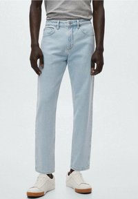 Jeans de mezclilla azul claro con un corte recto, diseño de cinco bolsillos y sutiles detalles de costura, combinados con zapatillas blancas.