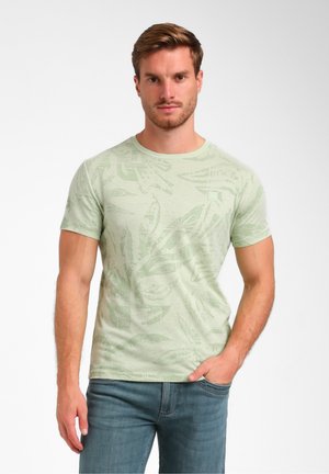 Lichtgroene T-shirt met korte mouwen, voorzien van een gestructureerd bladmotief, ronde halslijn en logodetail op de borst. Gecombineerd met blauwe spijkerbroek.