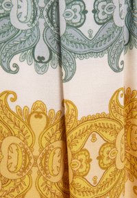 Tela de algodón con intrincados patrones de paisley en verde y amarillo sobre un fondo claro, que presenta motivos florales detallados y líneas fluidas.