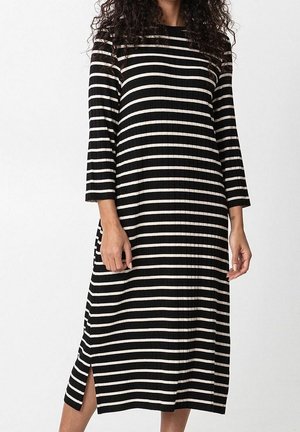 Schwarz-weiß gestreiftes Kleid mit dreiviertel Ärmeln, geripptem Stoff und seitlichen Schlitzen für mehr Bewegungsfreiheit.