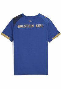 Královsky modrý športový dres s krátkymi rukávmi. Obsahuje zlaté písmená "HOLSTEIN KIEL" na chrbte a čierne ramenné akcenty. Hladký povrch.