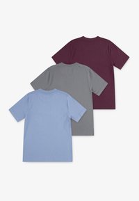 Tre enkle kortærmede bomulds T-shirts stablet, vist fra bagtagen, i blå, grå og mørk lilla farver på hvid baggrund.