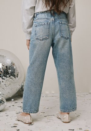 Világos farmernadrág magas derékrésszel, bőszárú fazonban, két hátsó zsebbel, kényelmes, flitteres papuccsal párosítva.