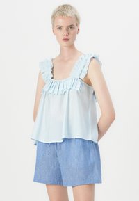 Lichtblauw mouwloos topje met ruches op de schouderbanden en een A-lijn ontwerp, gecombineerd met blauw-witte gestreepte shorts. Soepele stof, casual stijl.