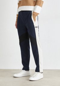 Marina joggerbyxor med svarta och krämfärgade sidpaneler, med dragsko i midjan och sidofickor. Matchas med vita sneakers.