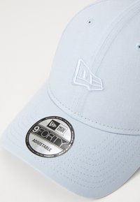 Boné azul claro feito de tecido, com um logótipo bordado e uma aba curva. Inclui um rótulo preto com a inscrição "9FORTY ADJUSTABLE."
