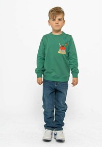 Grön sweatshirt med en tecknad dessertdesign på bröstet, i kombination med blå jeans och vita sneakers. Enkel, avslappnad passform och stil.