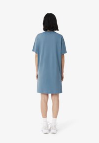 Abito t-shirt in cotone blu con maniche corte, vestibilità rilassata, scollatura rotonda e lunghezza al ginocchio. Design semplice senza motivi o accenti.