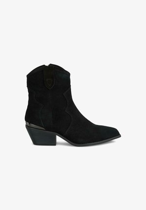 Botines de ante negros con puntera puntiaguda, costuras decorativas y un tacón bajo apilado. Presenta una cremallera en la parte posterior y un detalle de acento.