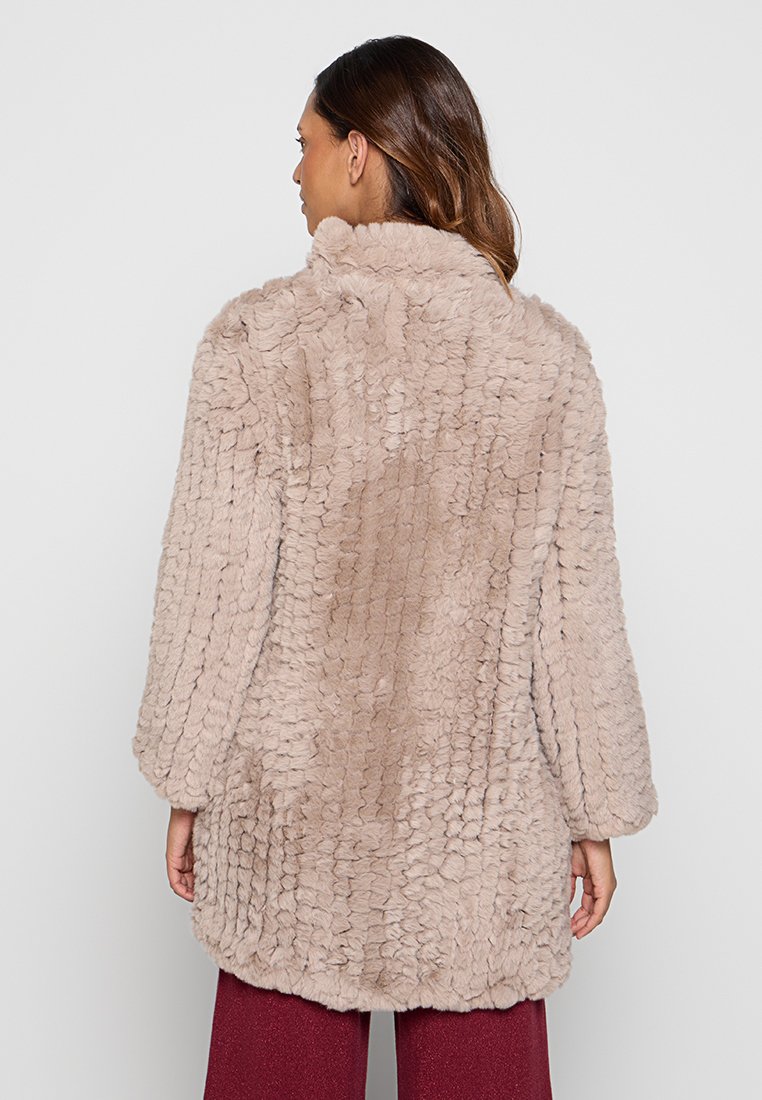 Beżowy płaszcz z sztucznego futra o teksturowanej powierzchni, w oversize'owym kroju, z obniżonymi ramionami i szerokimi rękawami, zaprojektowany z myślą o ciepłu i komforcie.
