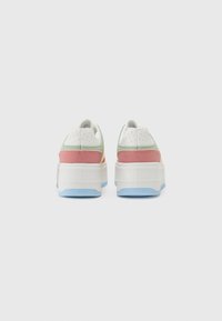 Baskets avec une tige en cuir blanc, des accents rose et vert pastel, et une semelle en caoutchouc bleue. Présente des détails perforés près du talon.